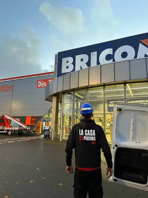 Un poseur de La Casa des Poseurs, casque sur la tête, devant un magasin où une enseigne va être posée