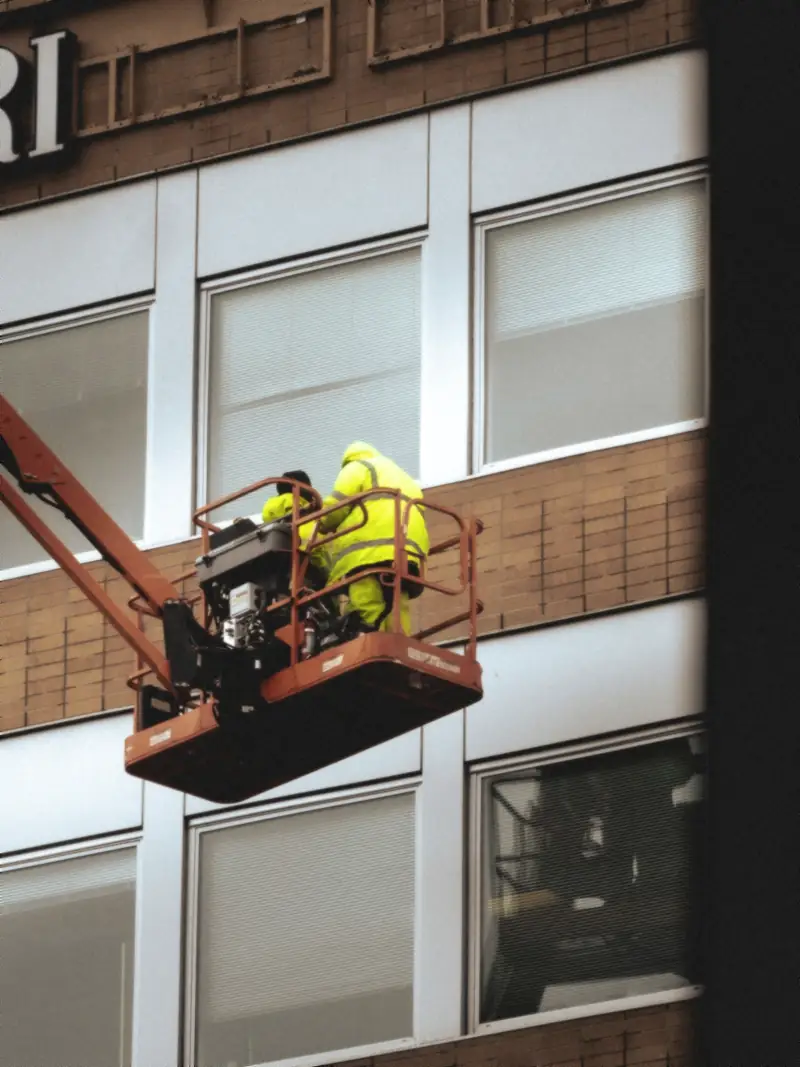 Deux poseurs en nacelle travaillent sur une façade